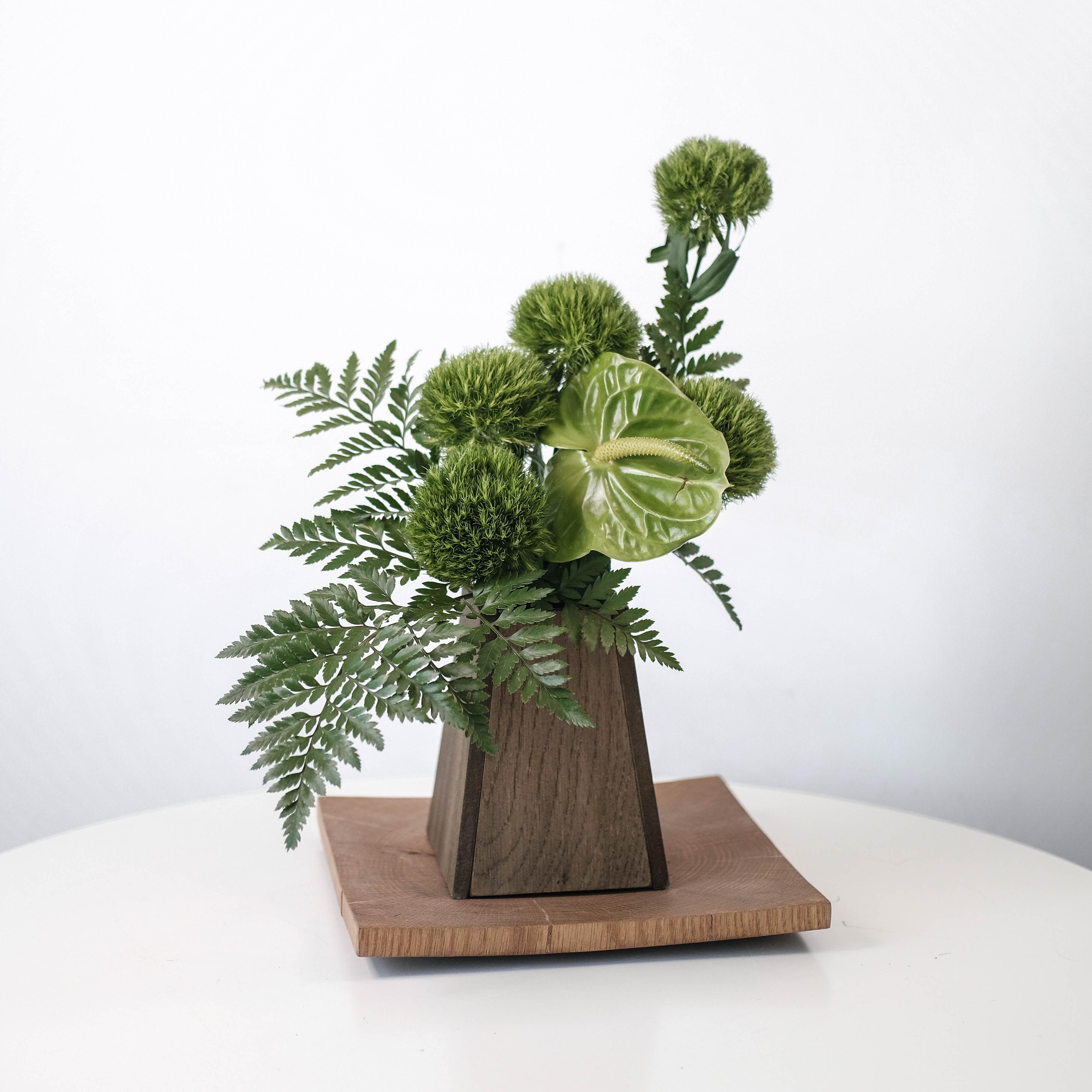 arrangement with green leaves and flowers on a wooden plant pot