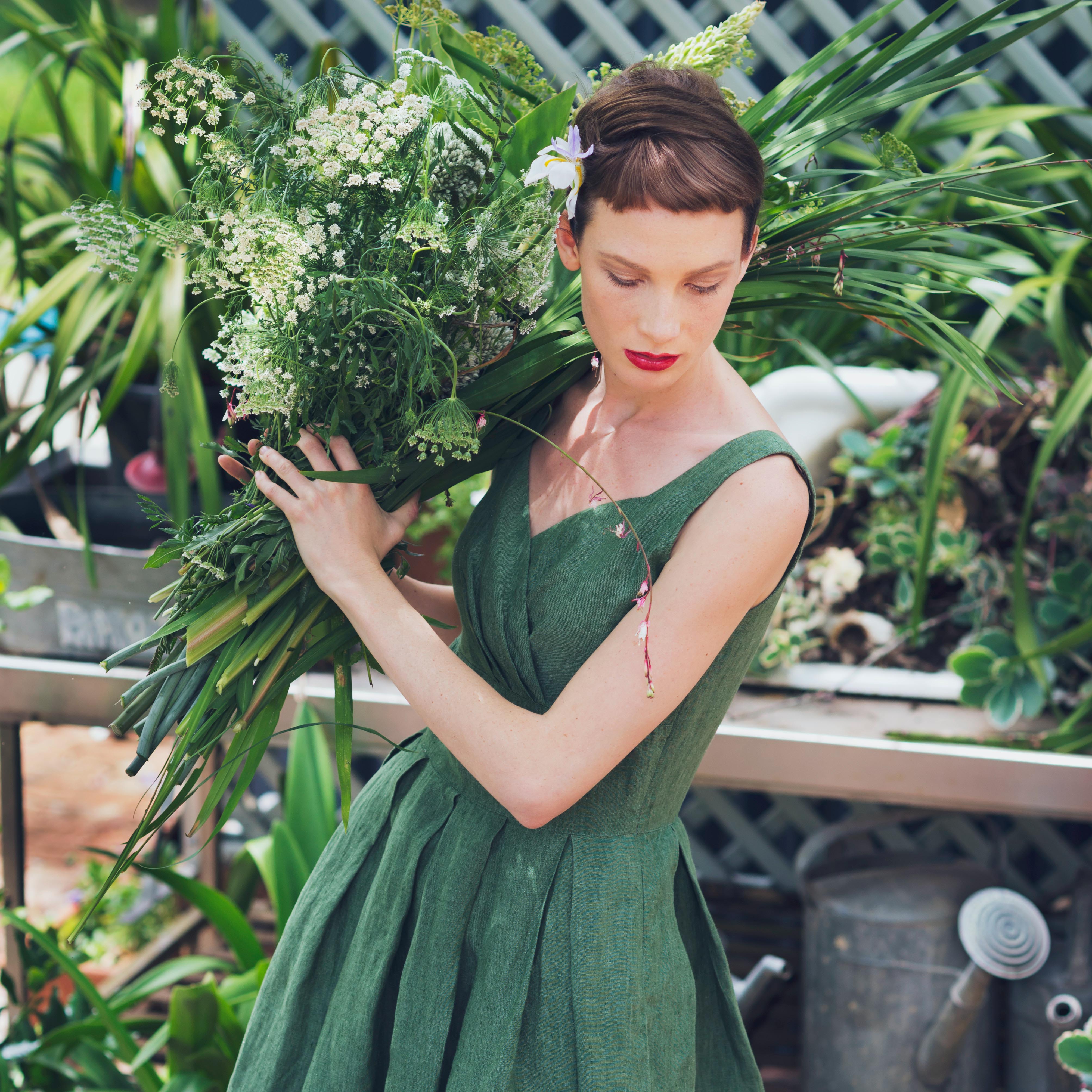 fashion model on a green dress holding a flower arrangement